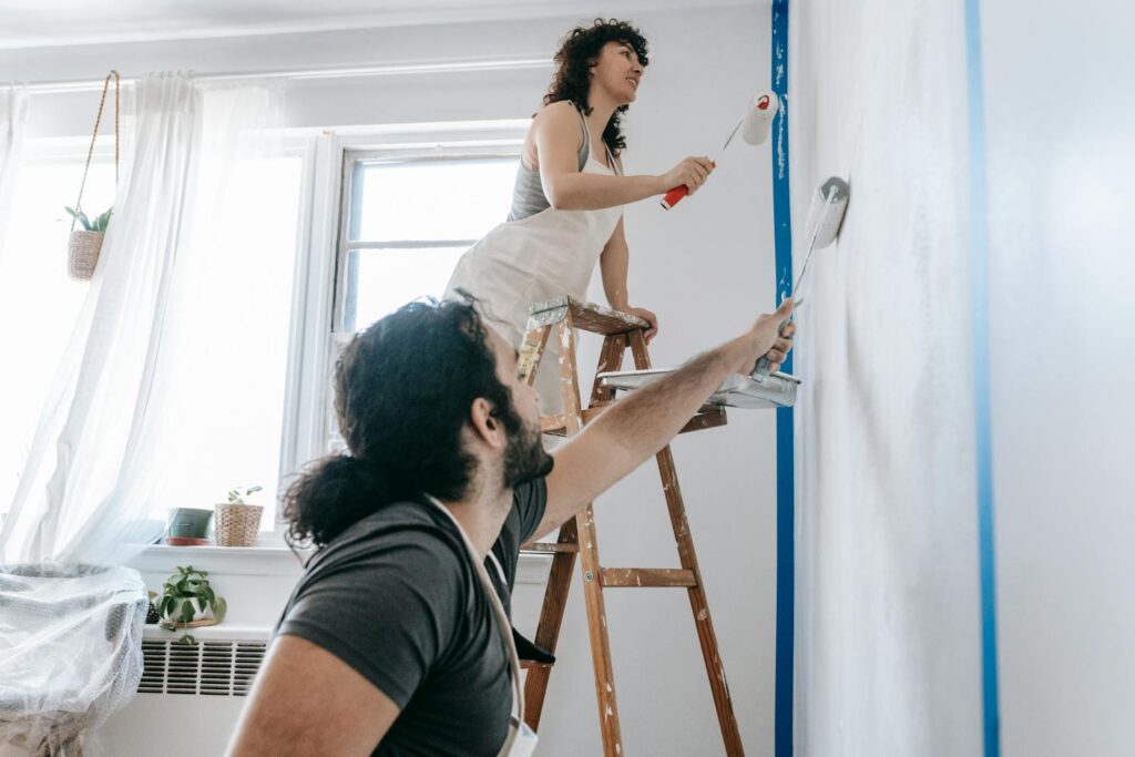 A couple engaged in a joyful home renovation, painting walls together.