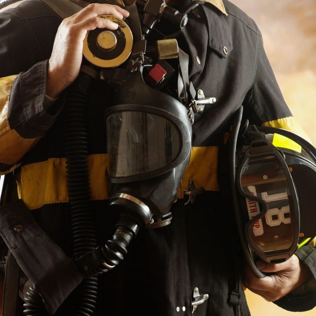 A person in black and yellow uniform holding a helmet.