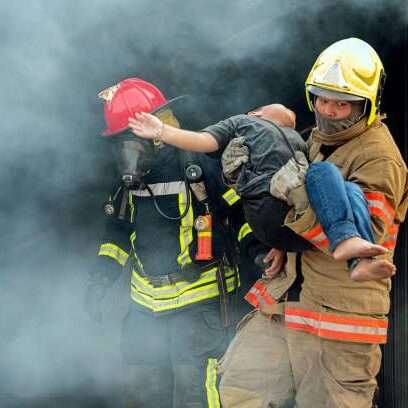 A fireman carries an infant through the smoke.